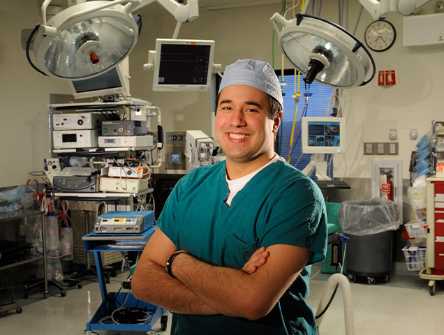 Xavier graduate standing in a surgical room wearing scrubs