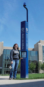 Photo of Student next to XUPD Assistance Telephone poll