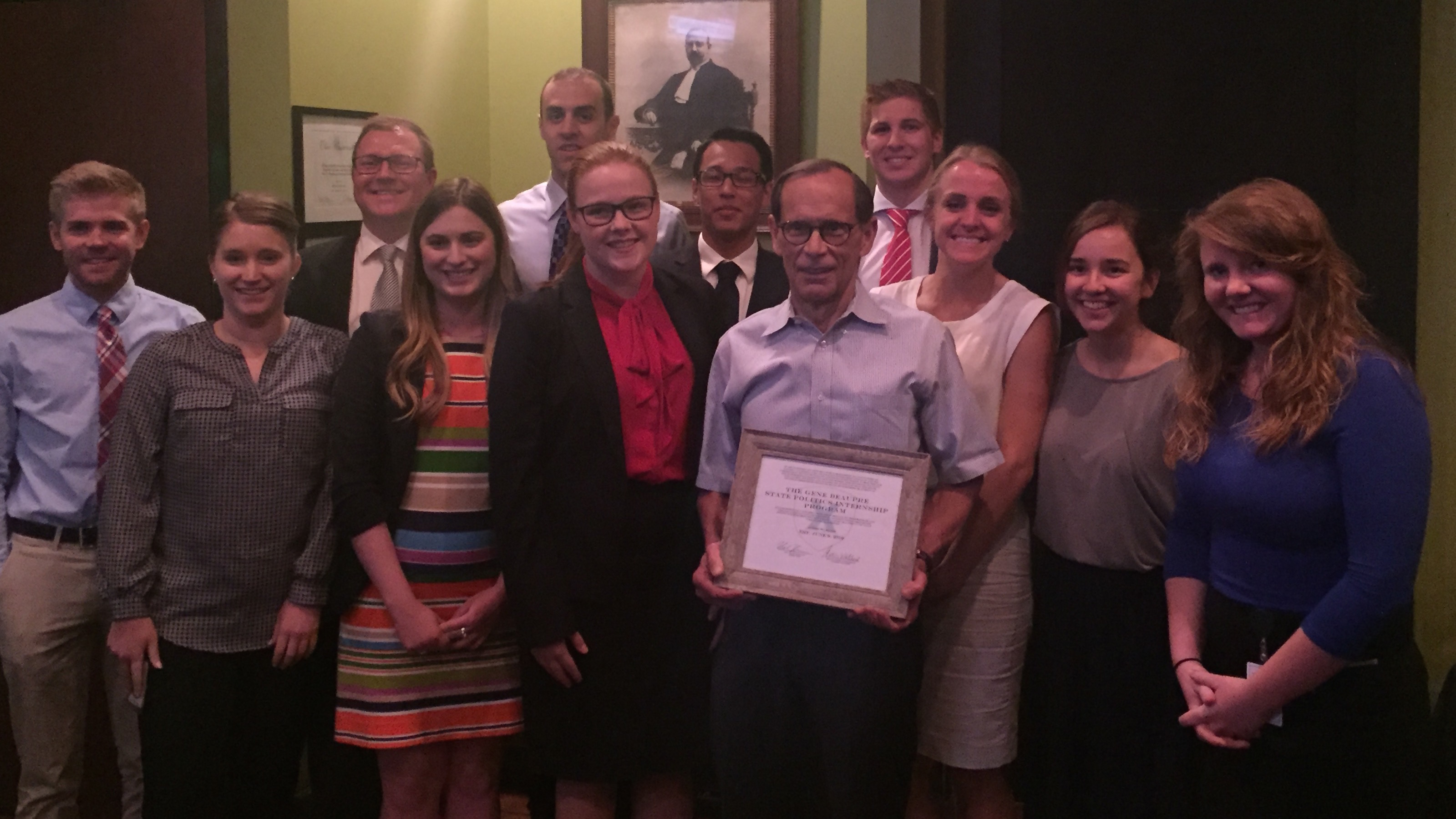 Student interns with state politicians holding a plaque