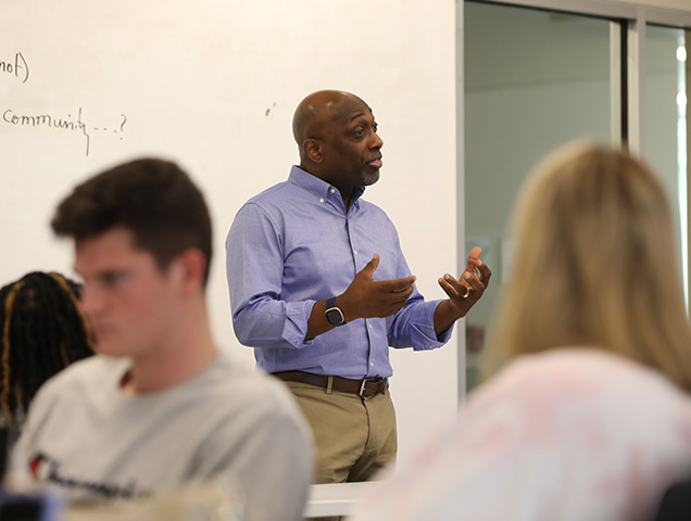 Professor leading a class in front of a chalkboard