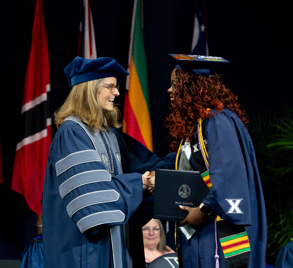President Hanycz presents a diploma to a student during the Xavier graduation ceremony
