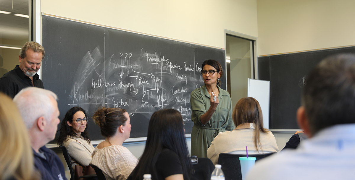 Professor leading a classroom in front of a chalkboard