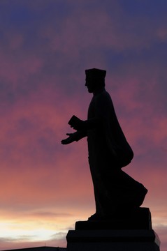 St. Francis Xavier statue in front of a sunset over campus.