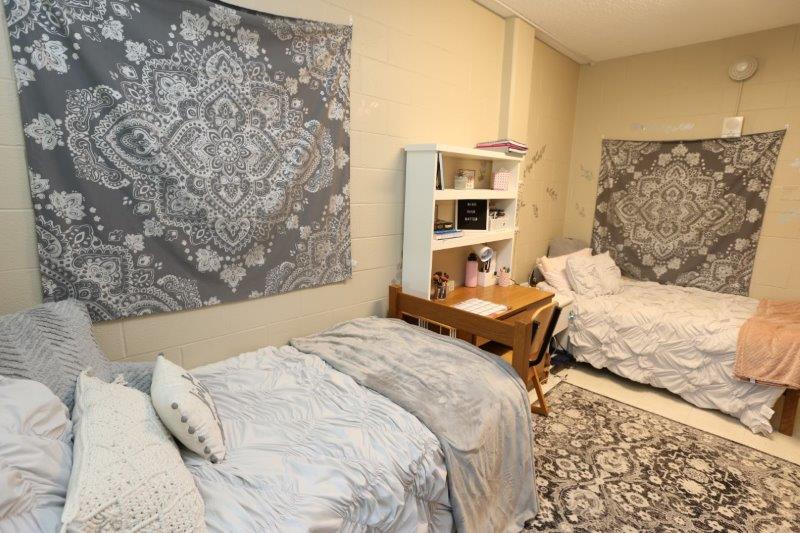 Husman double dorm room setup, showing a desk between two beds 