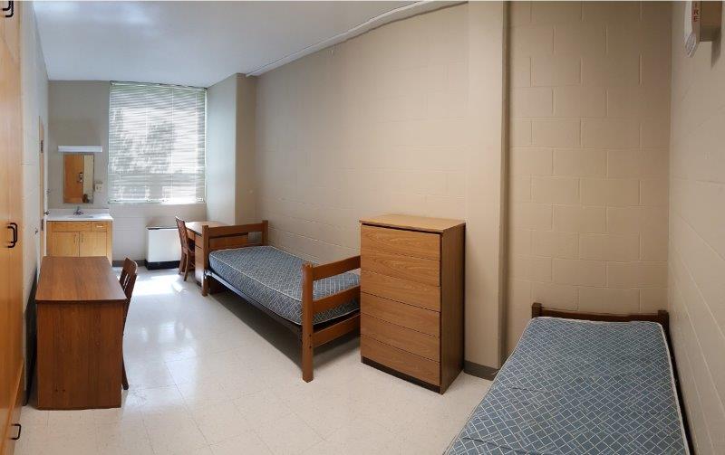 Unfurnished Kuhlman double hall room, showing beds, a sink, a desk and a dresser 