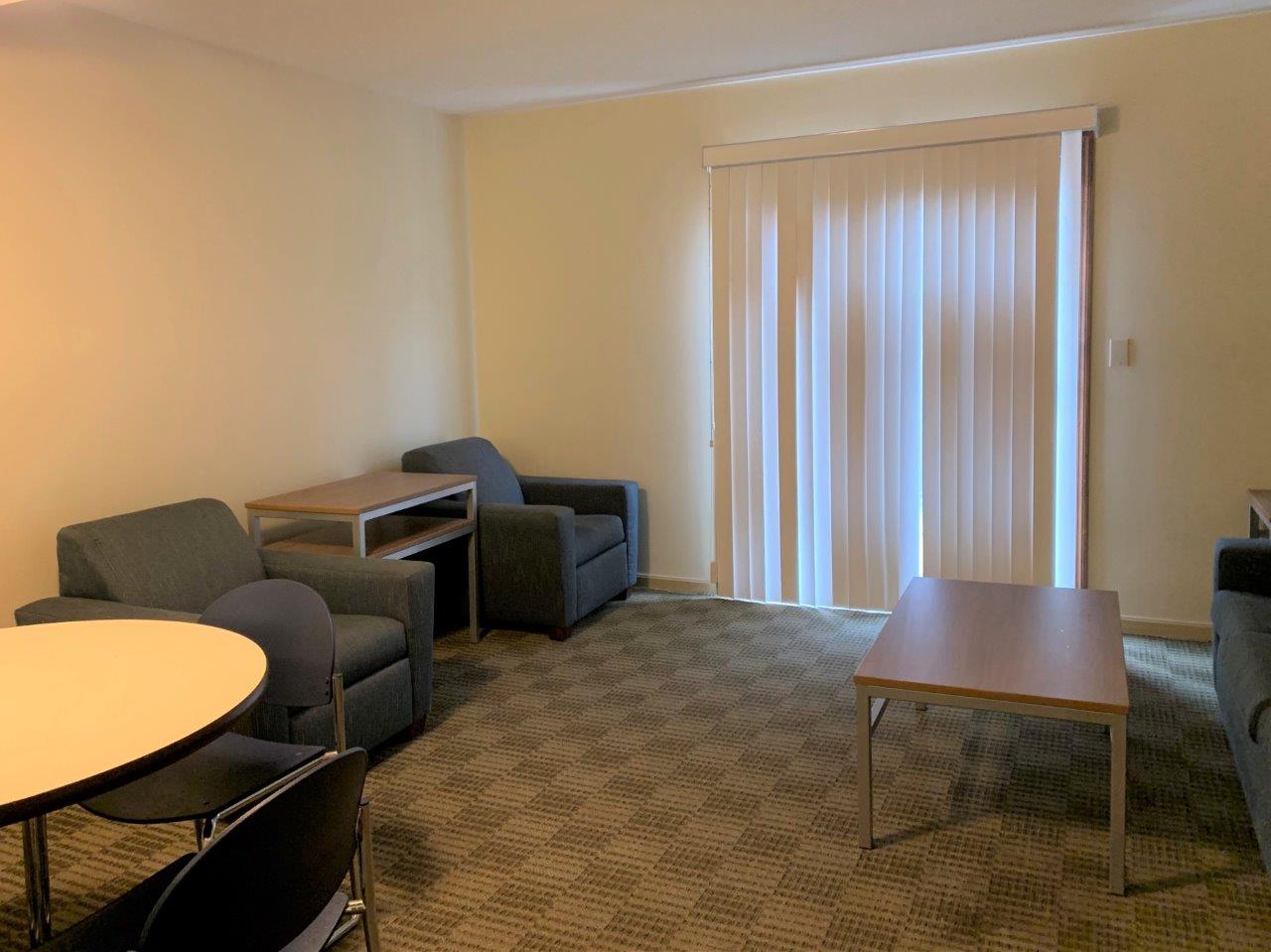 Village Apartments living room with chairs, a coffee table and a couch