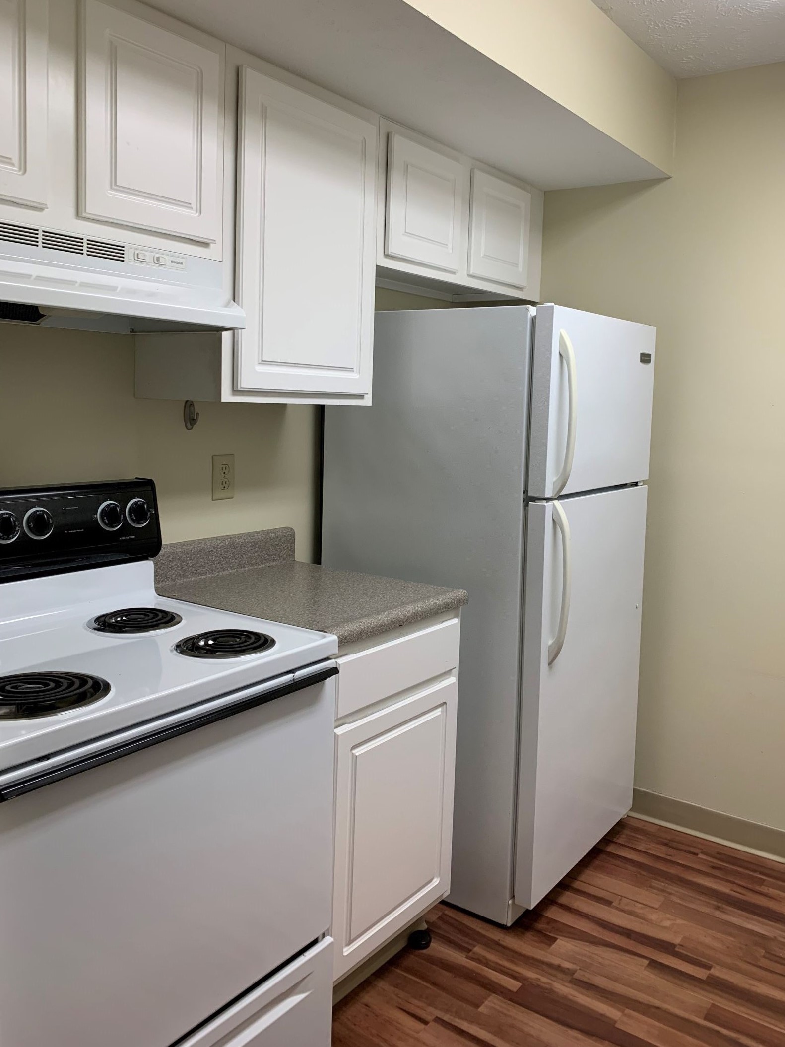 Village Apartments kitchen with white cabinets and refrigerator