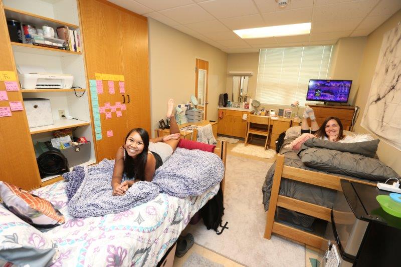 Furnished double room in Kuhlman showing two students lounging on their beds