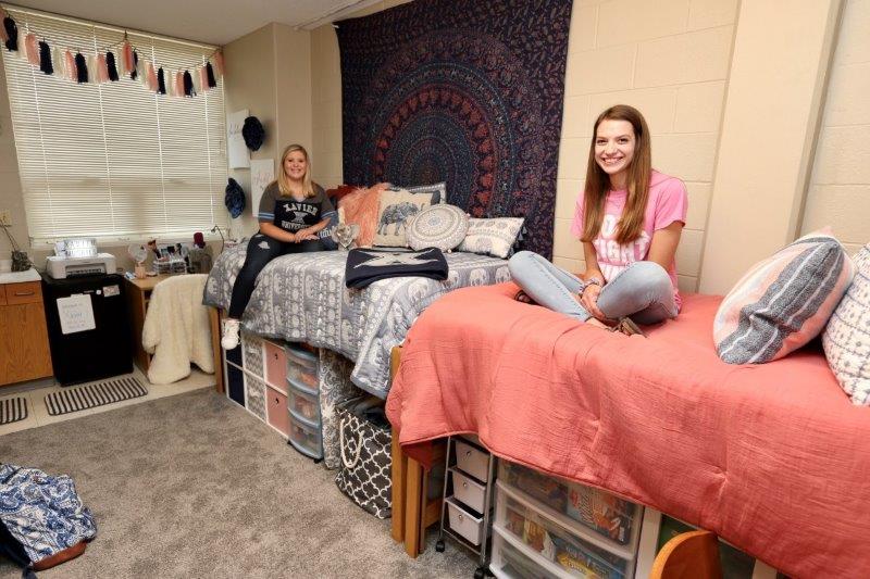 Furnished double room in Kuhlman showing two students sitting on their beds