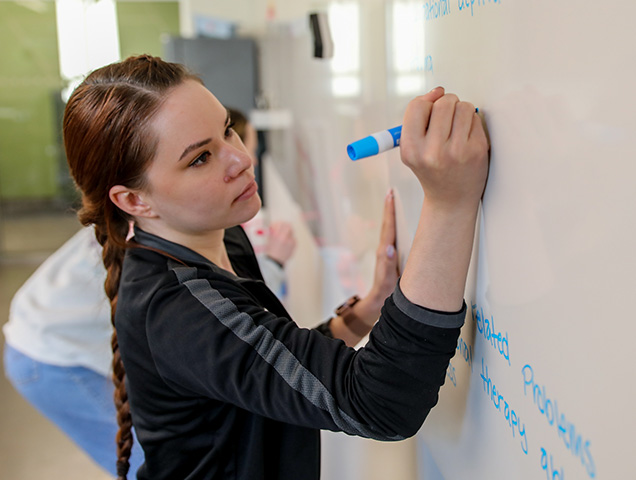 Student writing on a whiteboard in a classroom