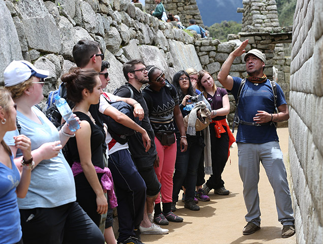 Students walking along stone wall in Peru