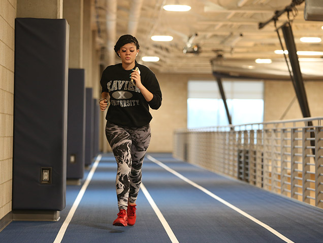 Student in the sport marketing major running on an indoor track in Xavier's recreation center