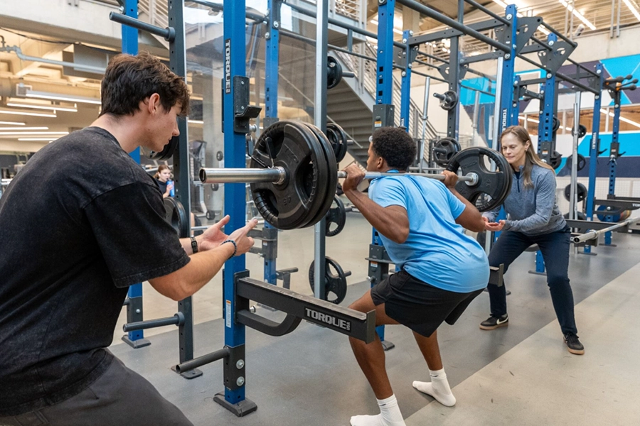 a student does a squat to lift weights