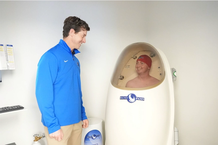A student looks at another student inside a Bod Pod