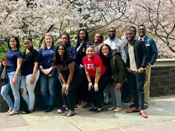 Group of Xavier students smiling together in front of a blossoming spring tree