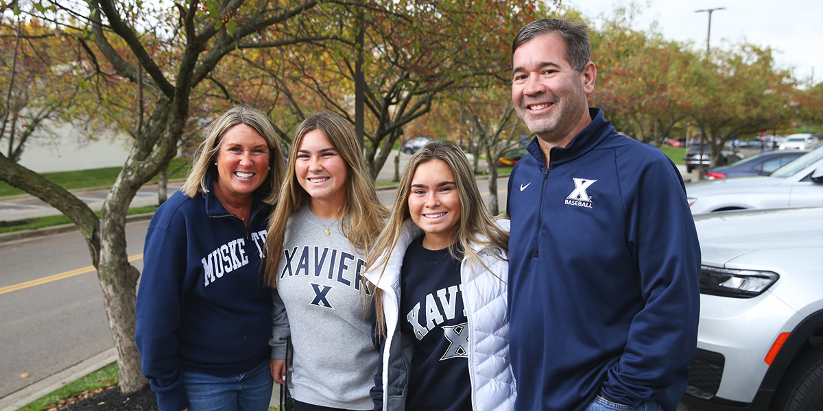 Two Xavier students smiling with their parents.