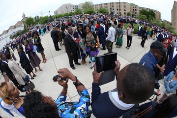 A picture of someone taking a photo of a graduate and her family during a commencement ceremony celebration