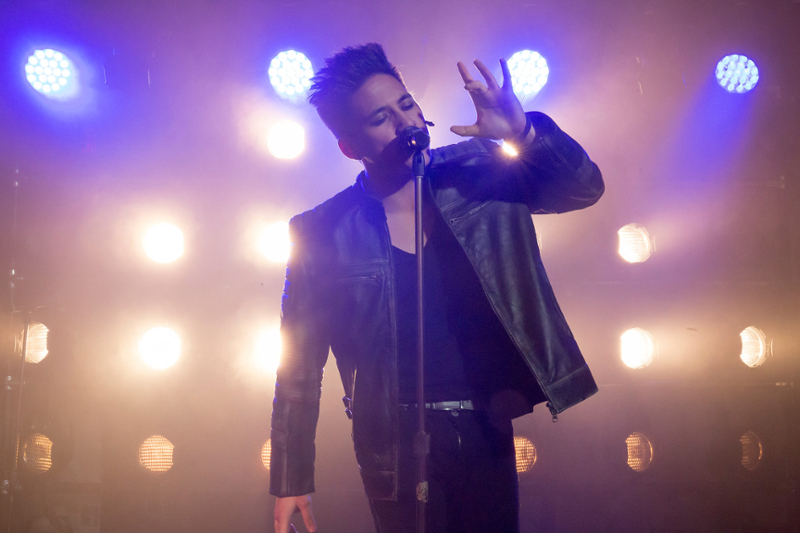 Actor singing into a microphone on stage