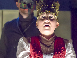 Close up of a theatre major on stage wearing a red robe and royal crown