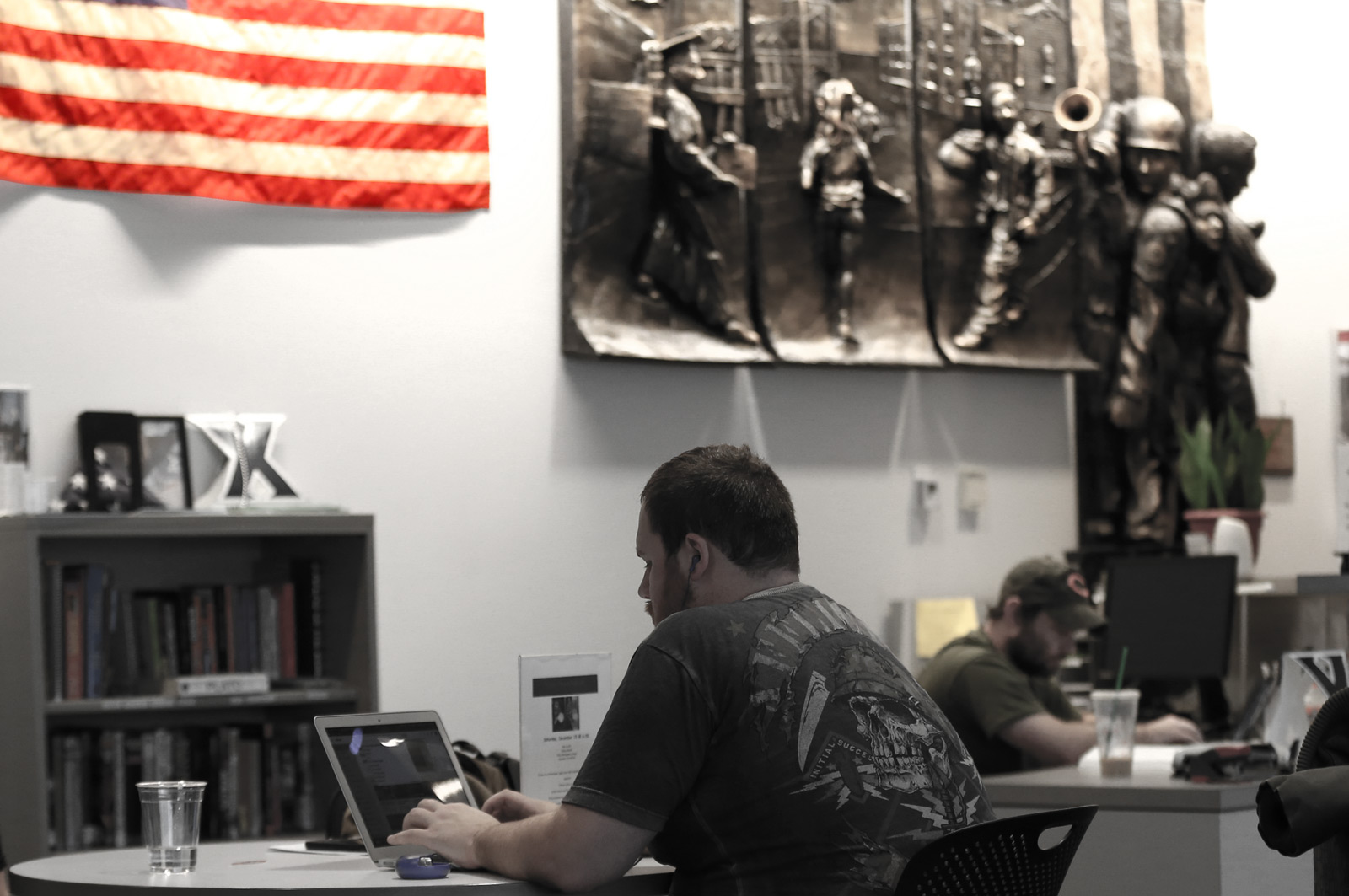 Two veteran students work on their laptops at desks inside the Veteran and Military Family Center.