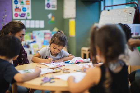 Photo of children coloring together at a table in a classroom